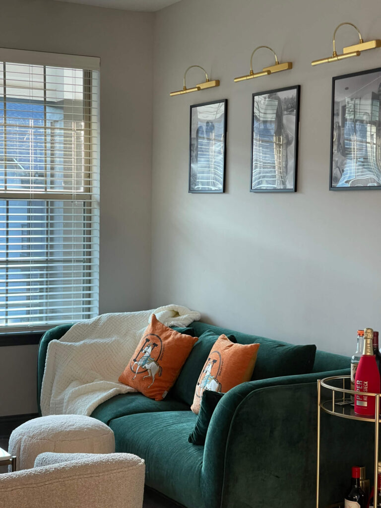 living room with green velvet couch and orange pillows