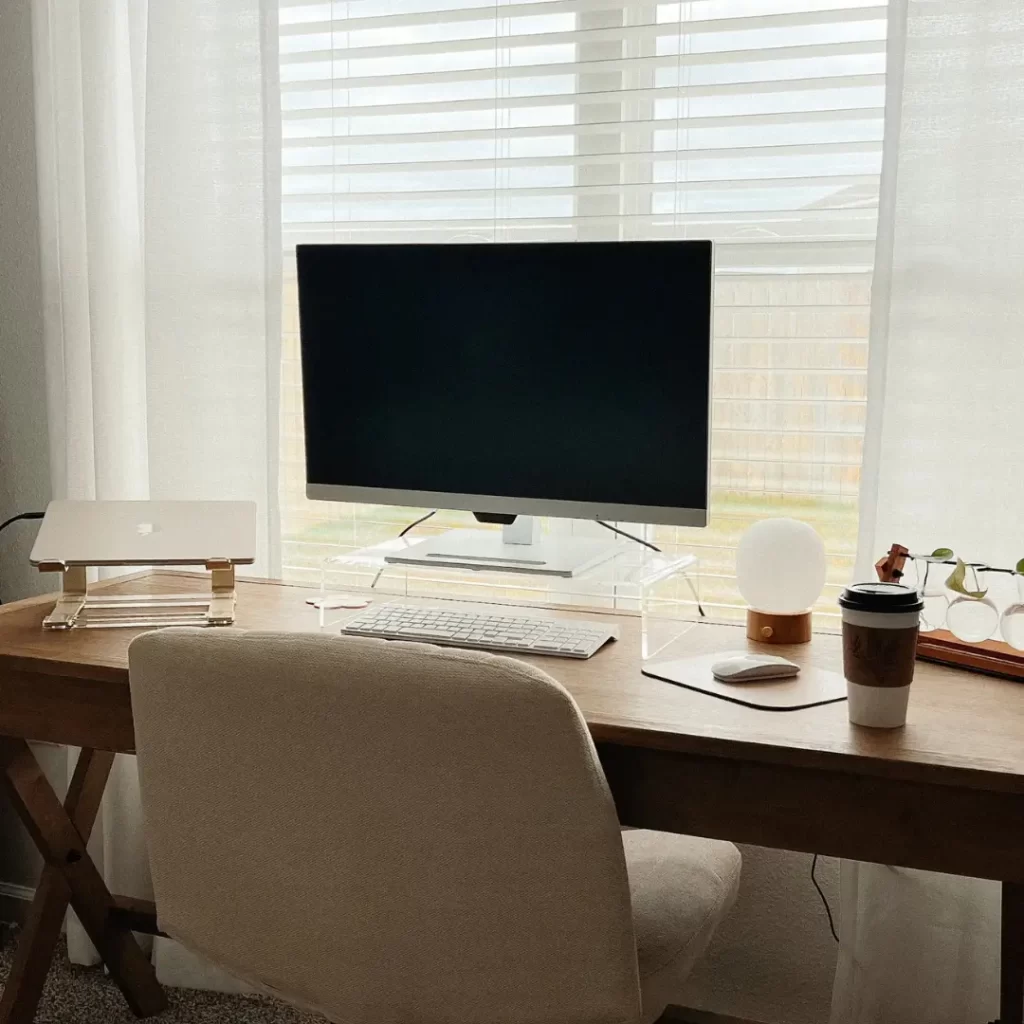 minimal home office, desk next to the window, screen and a laptop on a wooden desk, white office chair in front of the desk